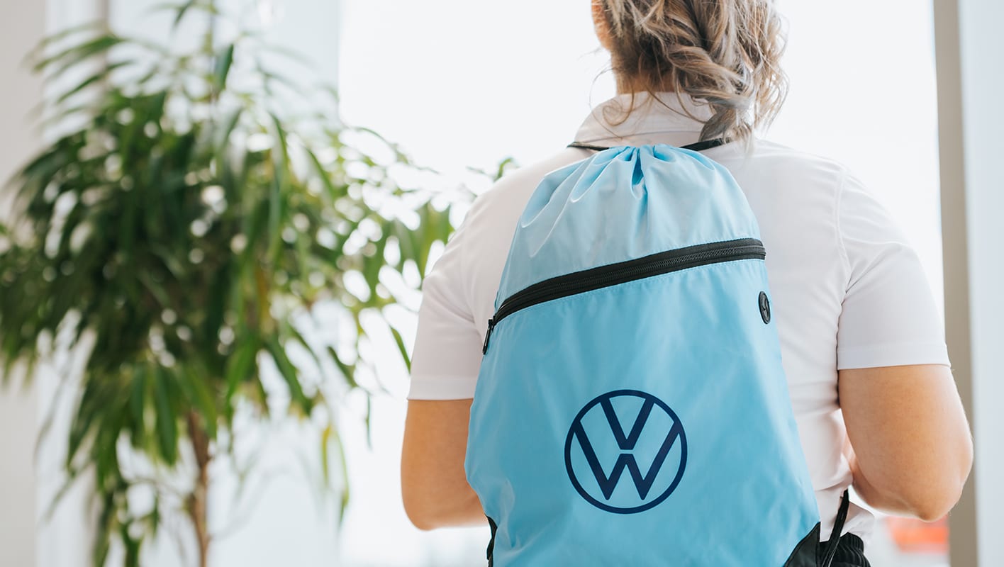 Jeune fille portant un sac à dos bleu avec le logo de Volkswagen